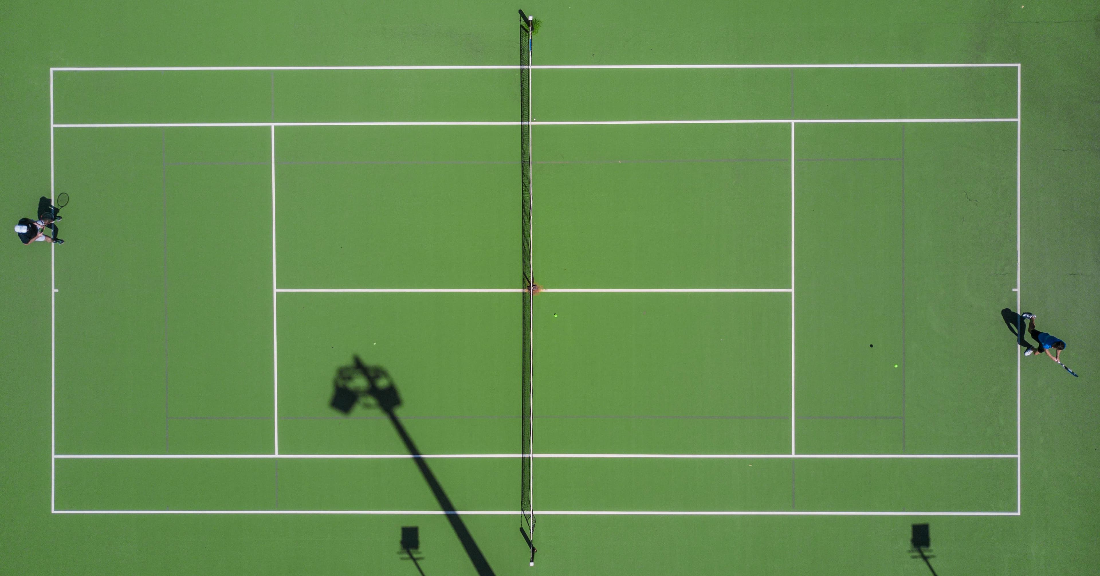 Aerial view of a tennis court with players mid-match
