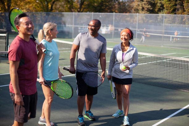 Diverse group of tennis players chatting on an outdoor court
