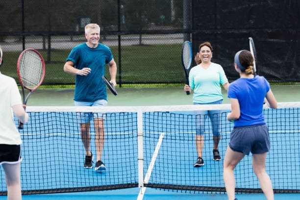 Players enjoying a doubles match on a blue tennis court